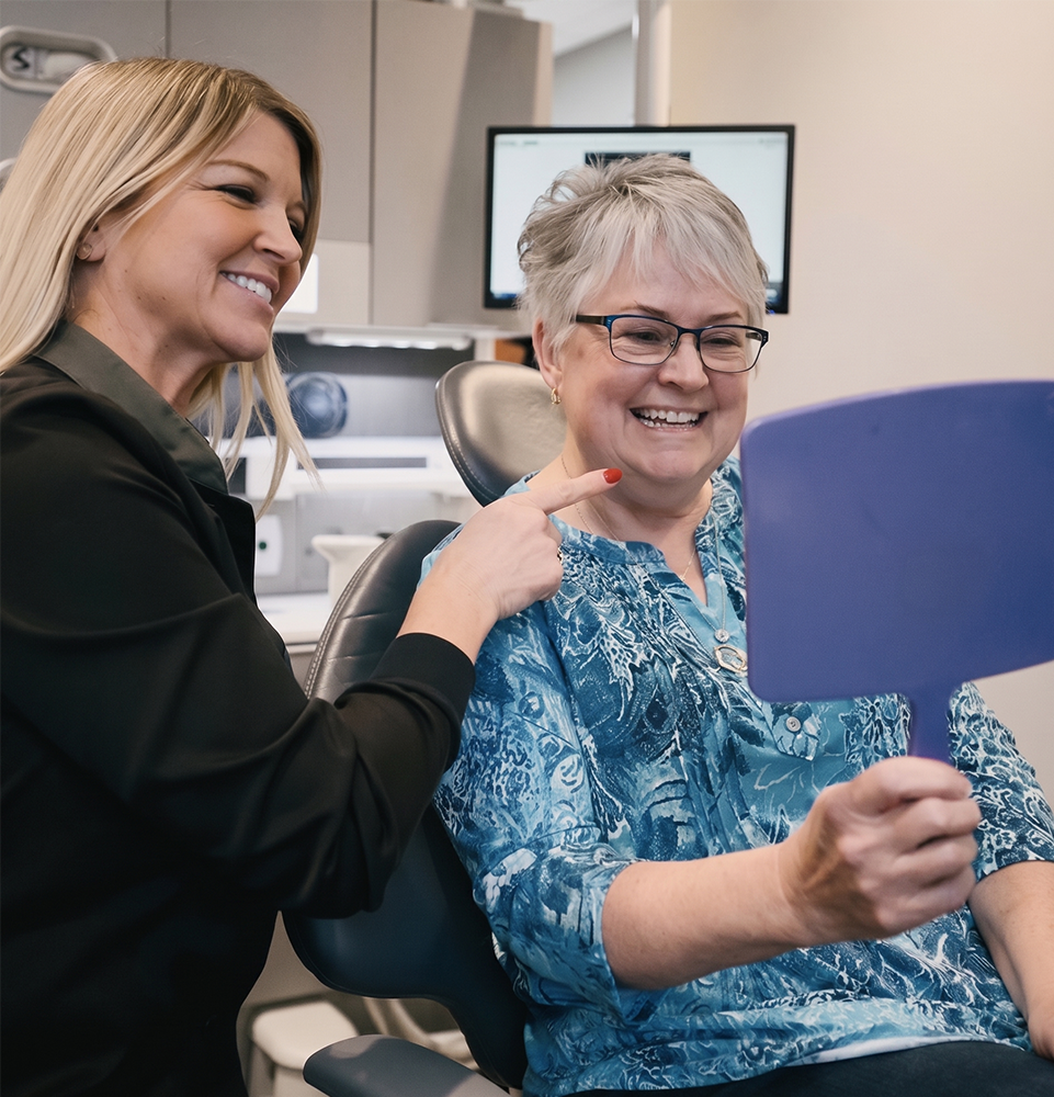patient smiling and holding a mirror